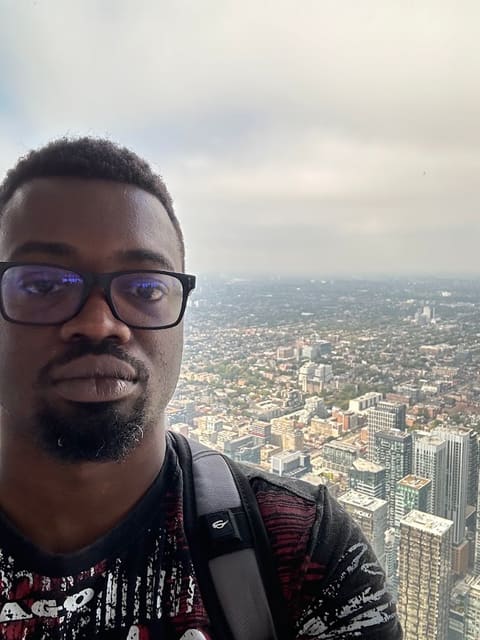 Dhul Wells in glasses, with a city skyline far below